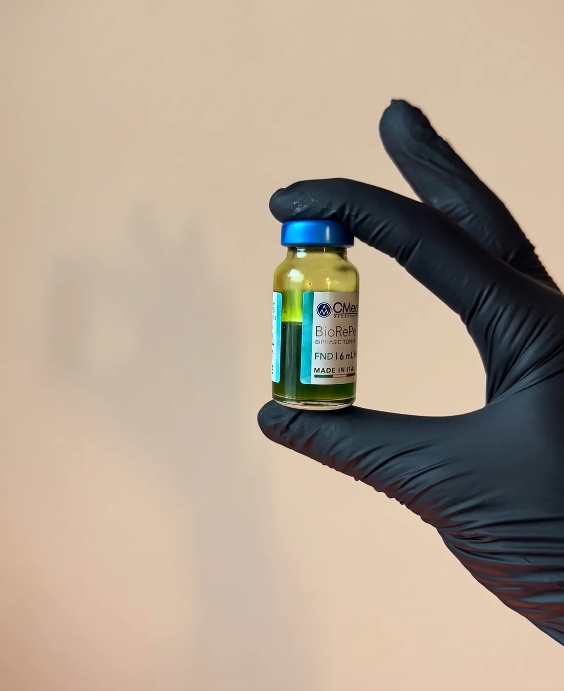 Flacon BioRePeel tussen vingers in een zwarte handschoen