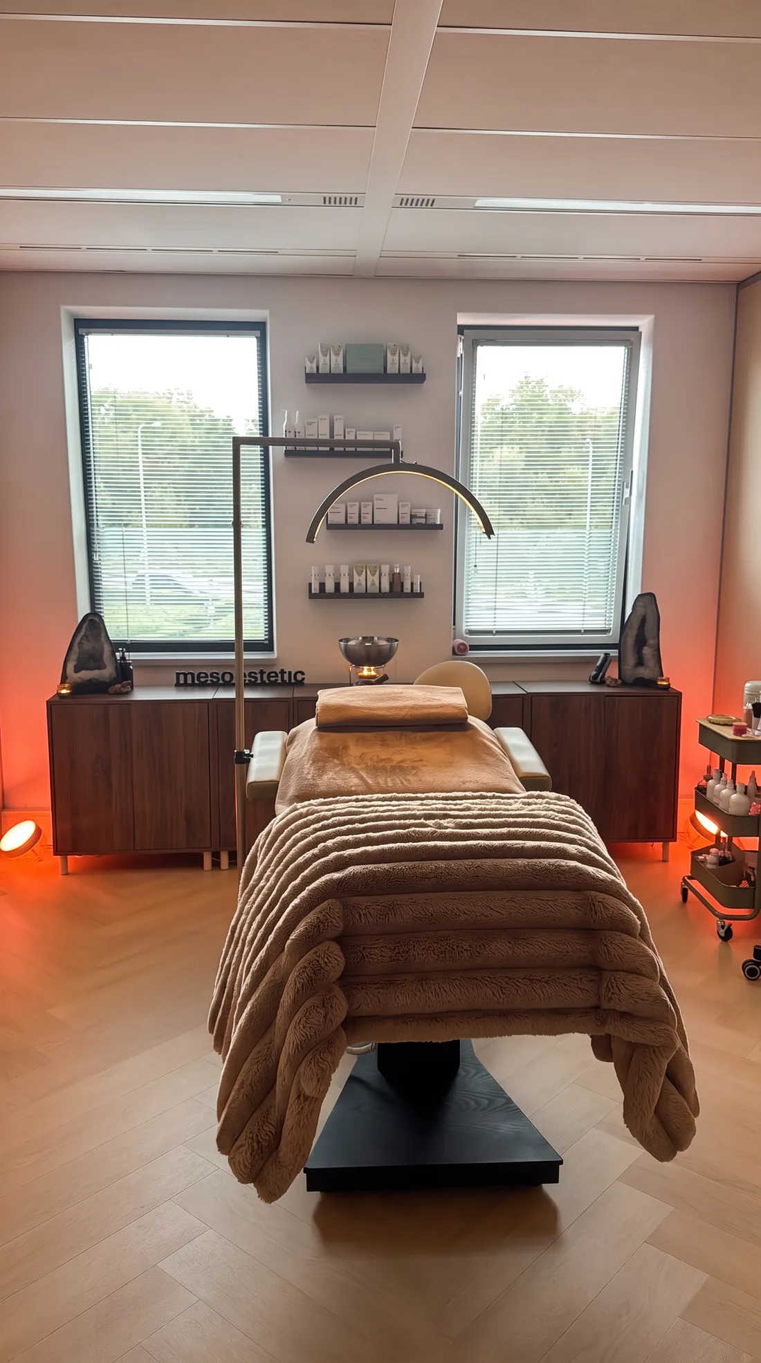 De behandelkamer met het bed onder een mokka pluche deken, de gouden booglamp en twee ramen
